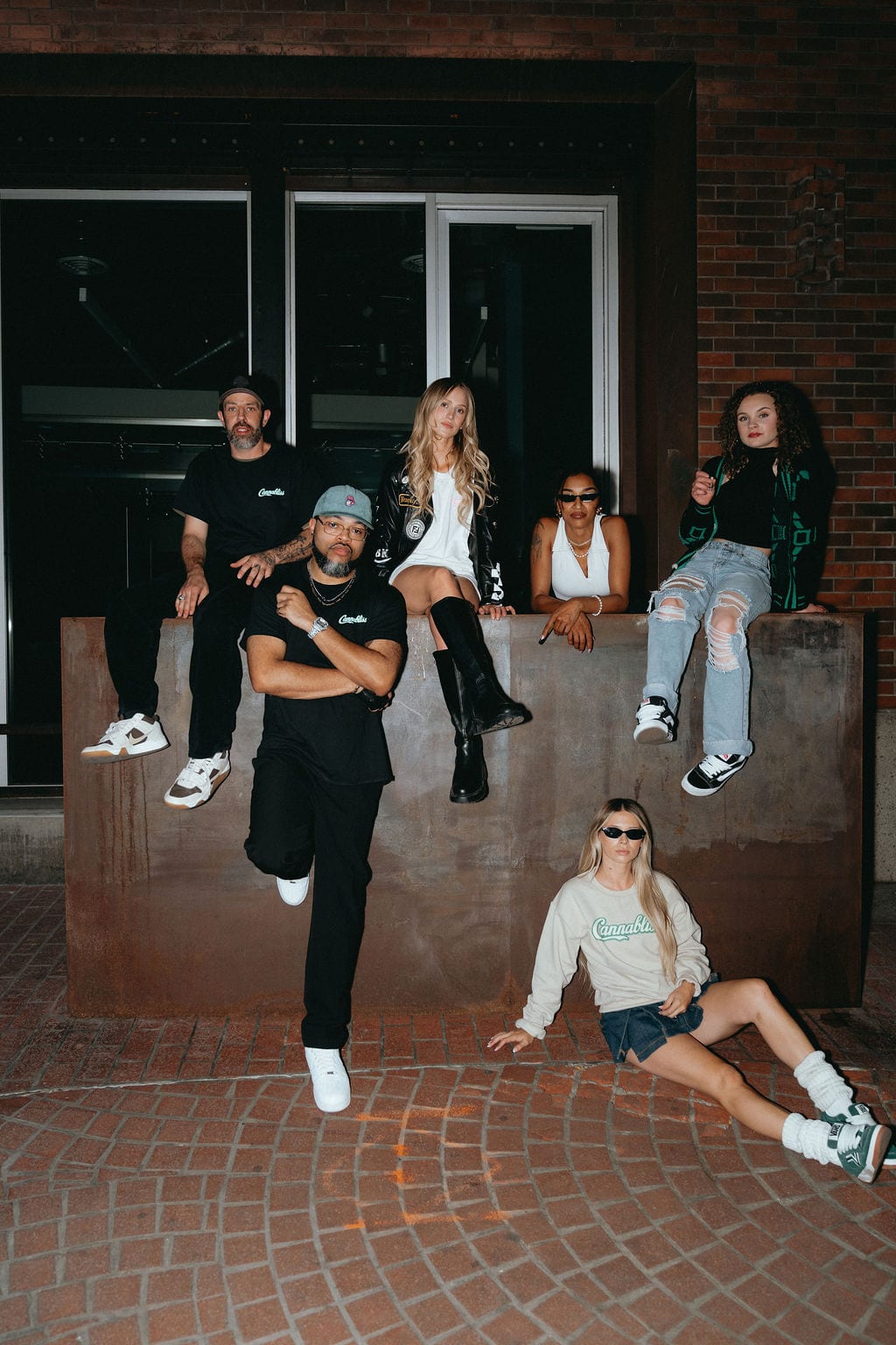 Six members of the Cannabliss crew, several in Cannabliss shirts, gathered outside a brick building.